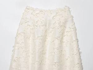 Detail van gebroken witte rok met hoge taille en getextureerde franjestof en zachte veren