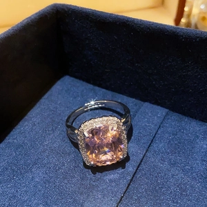Macro shot of cushion cut pink gemstone ring with halo zircons in a navy jewelry box