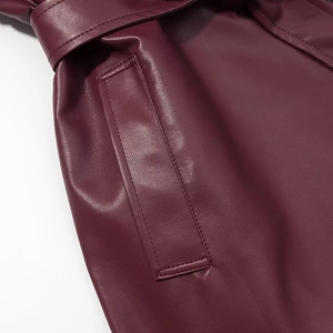 Détails des coutures de la poche et de la texture cuir du long manteau bordeaux