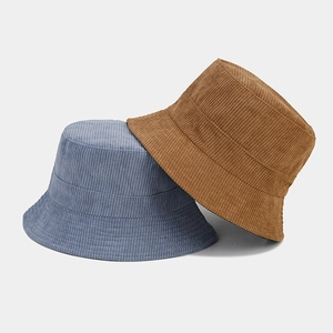 Navy blue and tan corduroy bucket hats stacked against a minimalist grey backdrop
