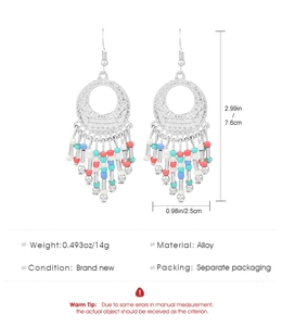 Dettaglio di orecchini boho in lega con perline rosse blu bianche e nappe pendenti