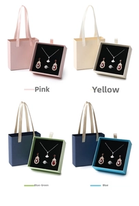 Detail view of four jewelry gift sets in pink, yellow, teal and blue with elegant packaging