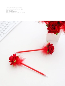 Detail of red rose artificial flower pens with feather trim on a minimalist white desk