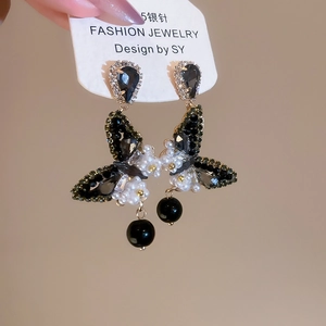 Close-up of gothic butterfly drop earrings with black crystals and pearl accents