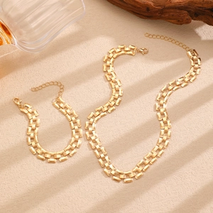 Detailed view of matte gold punk chain necklace and bracelet set on textured surface