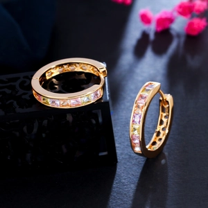 Macro detail of gold hoop earrings set with vibrant multi-colored square-cut zircons