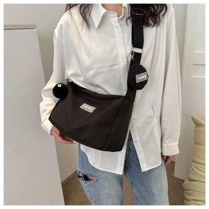 Détail du sac bandoulière en nylon noir avec porte-monnaie rond et breloque en peluche