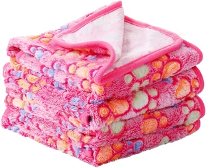 Close-up of soft pink flannel pet blanket featuring colorful paw prints and neat edging