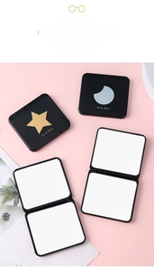 Close-up of portable square black makeup mirror with gold star and moon patterns