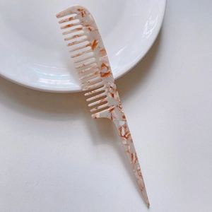 Detail view of marble pattern acetate tail comb resting on a white ceramic plate