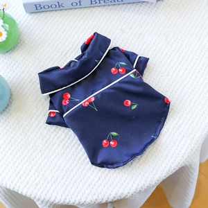Detail of silk-like pet pajamas featuring navy cherry print and white piping accents