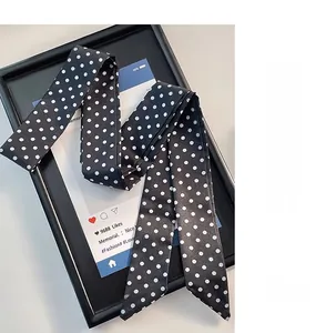 Gros plan détaillé d'un long foulard en soie noir et blanc à pois avec bouts pointus