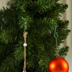 Close-up of S-shaped Christmas tree hooks in green and clear colors hanging ornaments