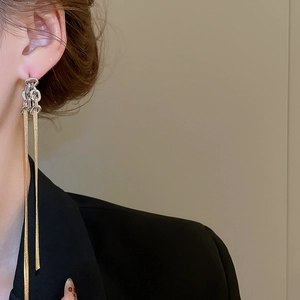 Détail de longues boucles d'oreilles pendantes bicolores avec chaînes sur un mannequin