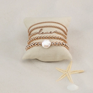 Bohemian rose gold 5-piece bead bracelet set with love charm and baroque pearl on sand