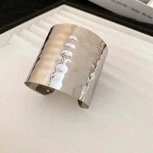 Macro detail of silver irregular hammered wide open cuff bracelet on white jewelry tray