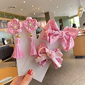 Detailed view of pink fabric bow hairpins and flower clips with tassels set for girls