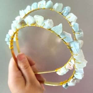 Detail of two handmade gold wire headbands with raw light blue natural crystal stones