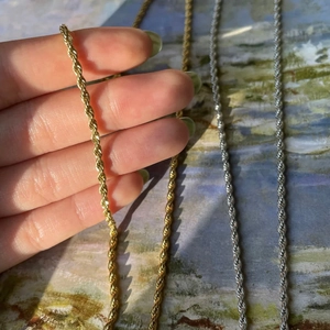 Dettaglio di catene a corda in acciaio al titanio oro e argento con trama intrecciata finissima