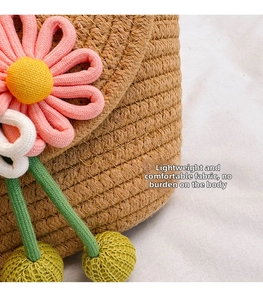 Detailed close-up of handmade straw bucket bag with knitted pink flower and plush charms