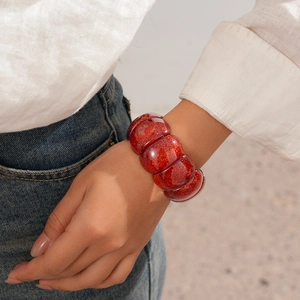 Detailansicht eines roten Acryl-Armbands mit Glitzerpartikeln und glänzender Oberfläche