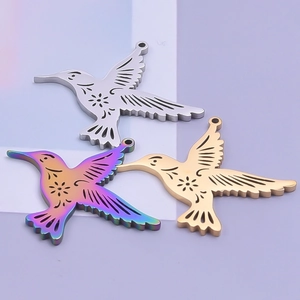 Macro detail of 18K gold and silver hummingbird pendants with floral hollow engravings