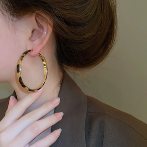 Detailed view of large leopard print hoop earrings with golden metallic accents on a model