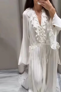 Detail of white bohemian maxi dress with ruffled collar and flared long sleeves