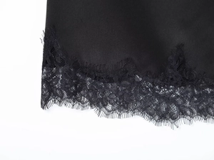 Detail of elegant black satin hem with delicate eyelash lace trim on a woman dress