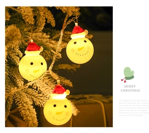 Detail of glowing snowman LED string lights with red hats on a snowy Christmas tree