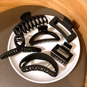 Set of 6 black geometric hair claws with hollow designs in a minimalist round tray