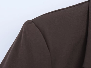 Detailed close-up of shoulder seam and dark brown fabric texture on a women's suit blazer