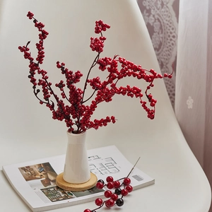 Vibrant artificial red berry branches in a white vase for festive home decoration