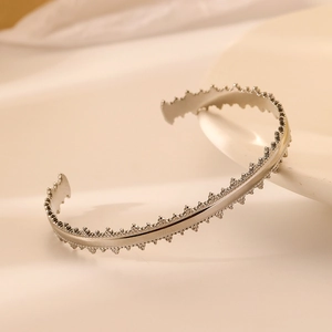 Detail shot of silver stainless steel bangle featuring unique jagged edge texture design
