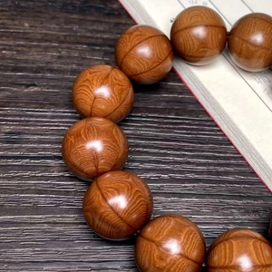 Macro shot of 15-20mm dark brown wood prayer beads with polished tiger-skin grain texture