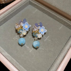 Detail of blue resin flower earrings with pearls and crystals in a velvet jewelry box