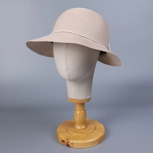 Détail du chapeau de paille beige clair avec chaîne de perles et texture tissée