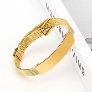 Détail du bracelet à maille dorée avec boucle réglable sur fond de magazine moderne