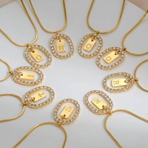 Close-up of gold snake chains with oval pavé-set diamond pendants and letter tags