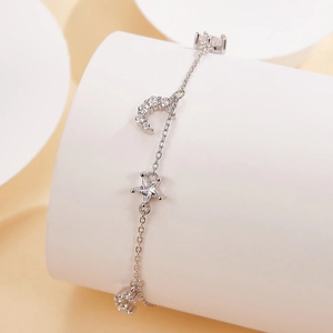 Macro shot of silver S925 star and moon bracelet with zircon pendants on white stand
