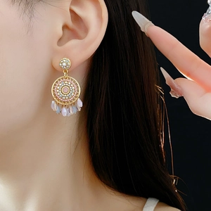 Detailed view of gold earrings with pink pearls and light purple crystal tassels