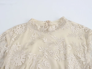 Dettaglio del ricamo floreale su tulle beige con colletto alto e cerniera nascosta