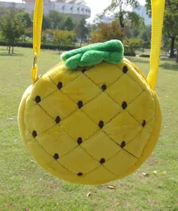 Detail of pineapple plush crossbody bag with textured yellow fabric and green leaves