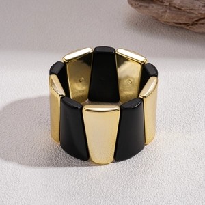 Detail of geometric black and gold acrylic stretch bracelet with polished metallic finish