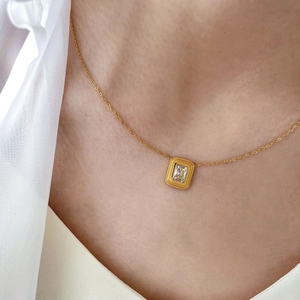 Close-up of minimalist gold zircon necklace with a rectangular cut stone on a model