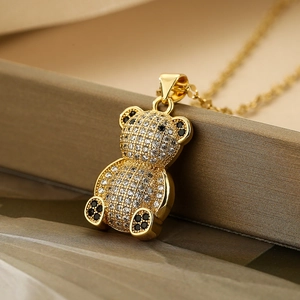 Golden teddy bear necklace with clear zircons and black gemstones on a brown jewelry box