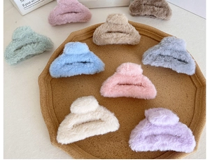 Détail de diverses pinces à cheveux en peluche aux couleurs pastel sur un plateau en bois