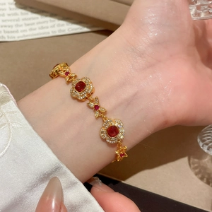 Close-up of vintage flower bracelet with red gemstone and gold beads on wrist
