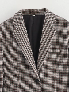 Detail of single-button houndstooth blazer showing brown and green woven fabric texture