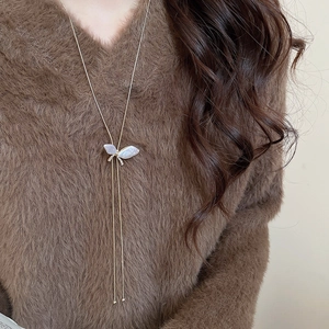 Close-up of butterfly pearl pendant long necklace on brown sweater for women